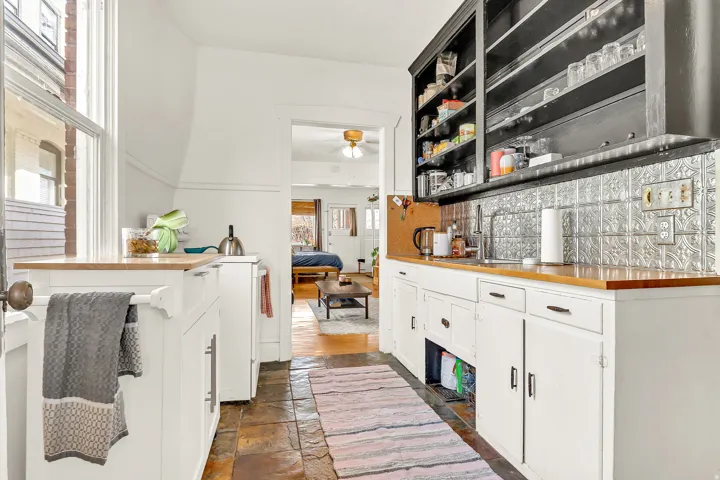 Kitchen featuring tile flooring, white cabinetry, wood-finish countertops, a stainless steel sink, and a pressed tin backsplash