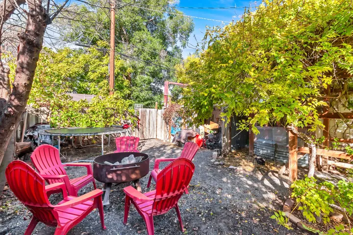 Outdoor area with a built-in fire pit, surrounded by mature trees and natural ground cover