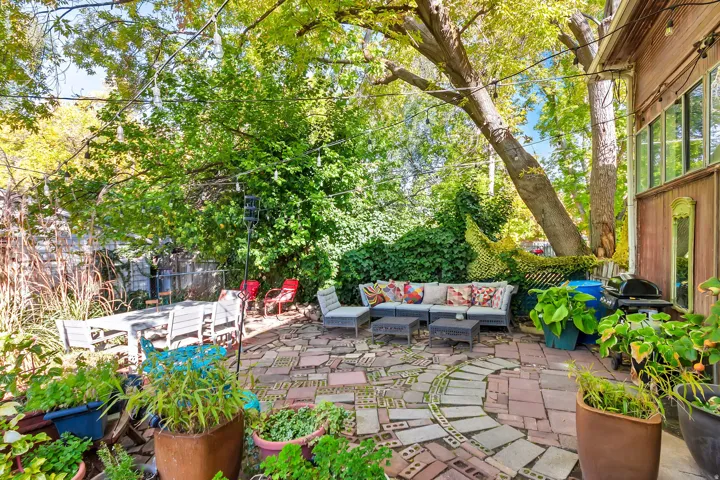 Expansive brick paver patio with a curved pathway and mature trees providing natural canopy