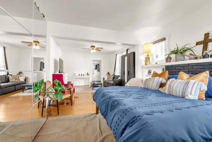 Open-concept living area with wood-finish flooring, white walls, and ceiling fans