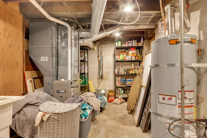 Utility room with exposed ductwork, concrete flooring, and water heater