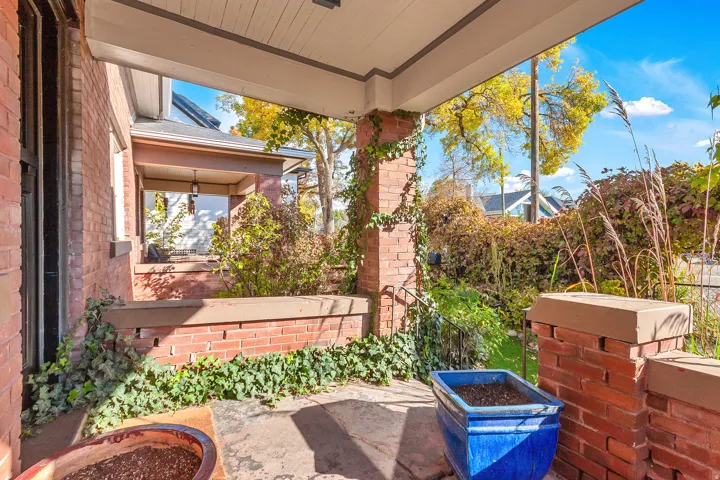 Brick exterior with a covered porch, concrete flooring, and an integrated brick planter box