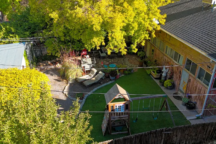 Expansive backyard featuring artificial turf, a stone patio, and mature landscaping