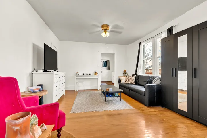 Wood-finish flooring, white walls, and a ceiling fan