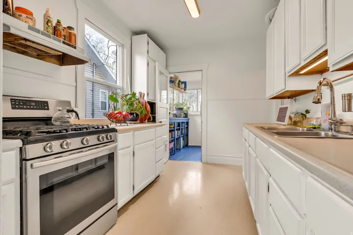 Stainless steel gas range, white cabinetry, undermount double basin sink, and recessed lighting