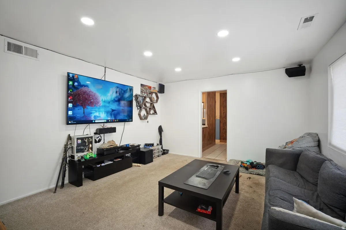 Recessed ceiling lighting, wall-mounted speakers, and a doorway with wood-finish flooring