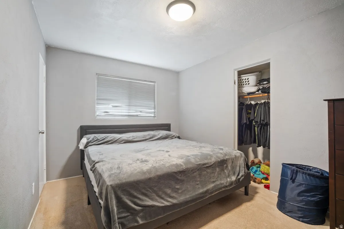 Recessed window with blinds, overhead flush mount lighting, and built-in closet with shelving and hanging rod