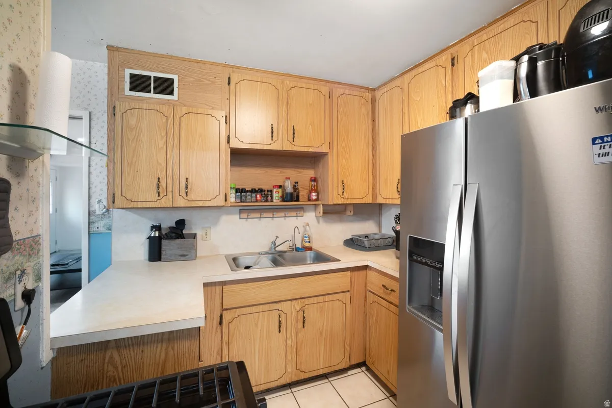Kitchen featuring wood-finish cabinetry, a stainless steel side-by-side refrigerator, and a double basin sink
