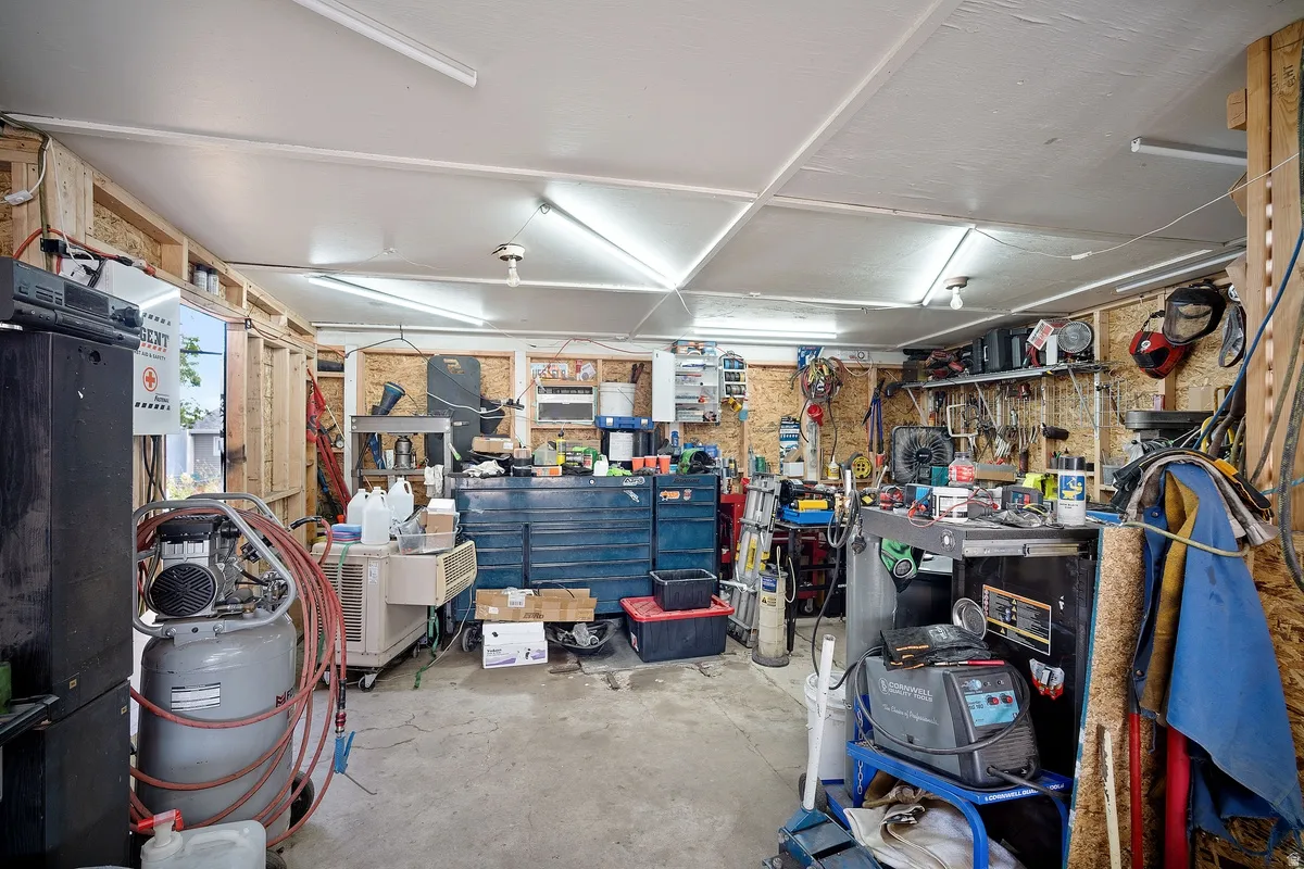 Concrete flooring, exposed wood framing, fluorescent lighting, built-in shelving, and a finished ceiling