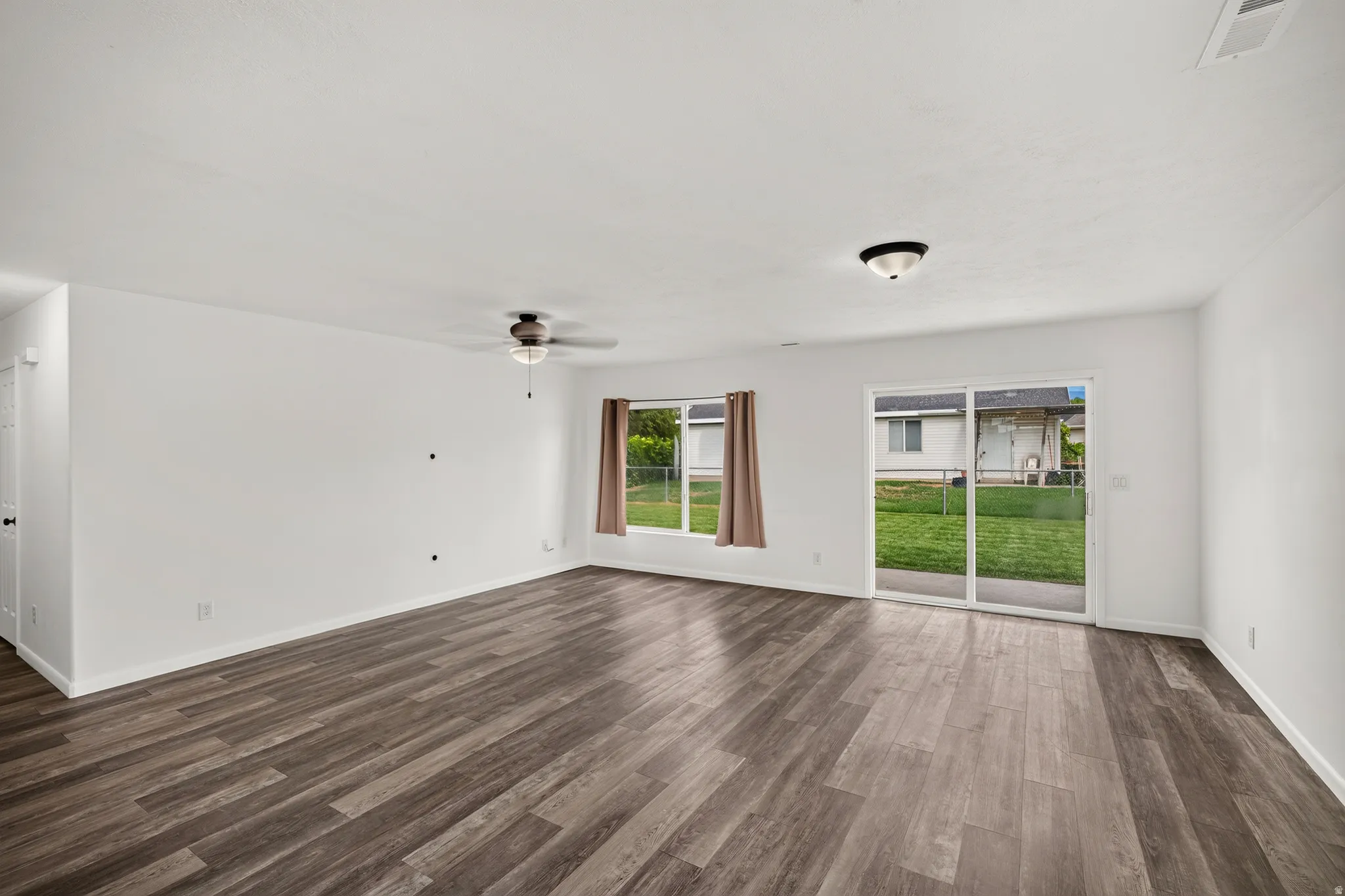 Spacious room featuring wood-finish flooring and a ceiling fan