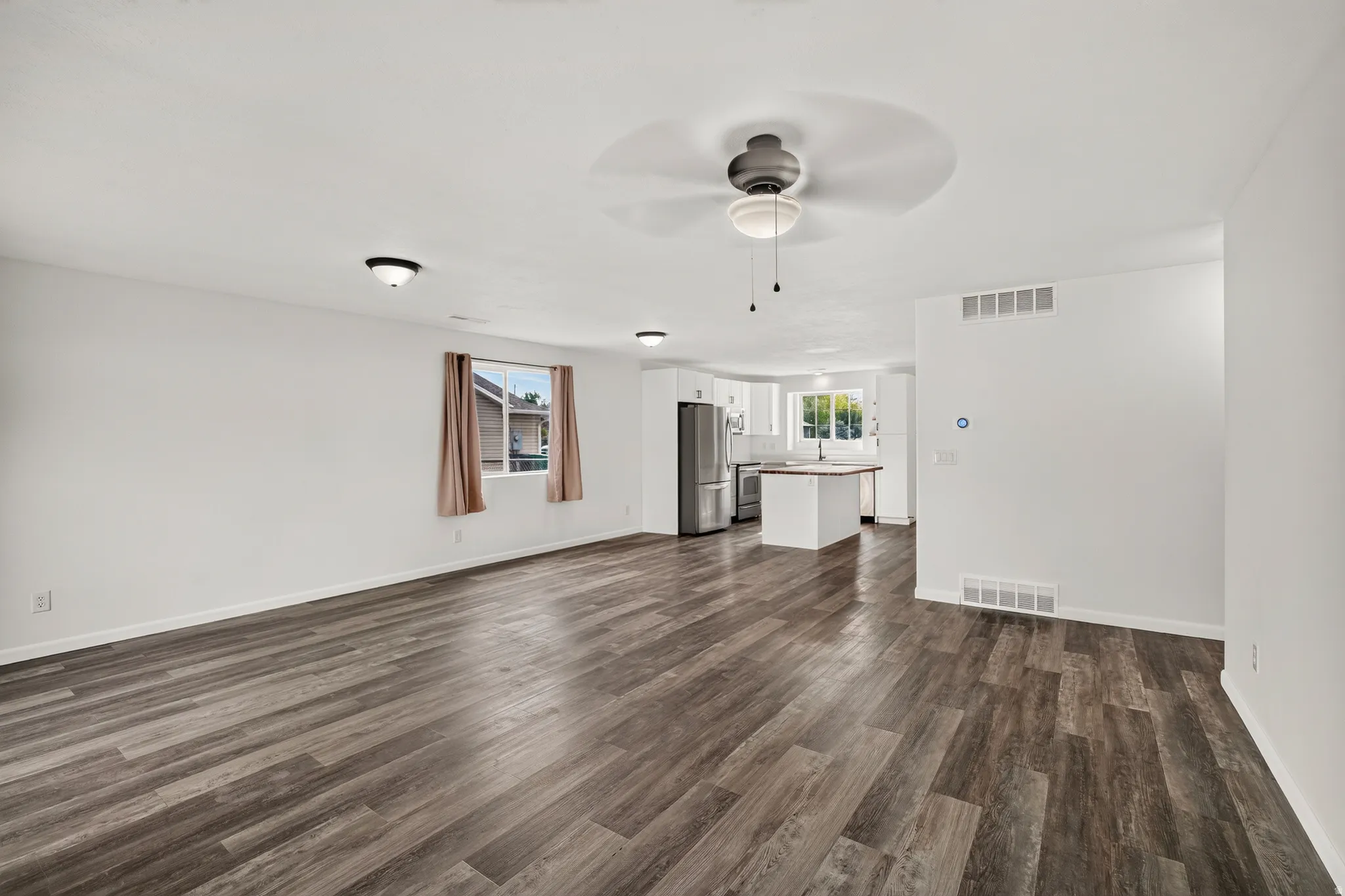 Spacious open-concept room featuring wood-finish flooring, a ceiling fan, and recessed lighting