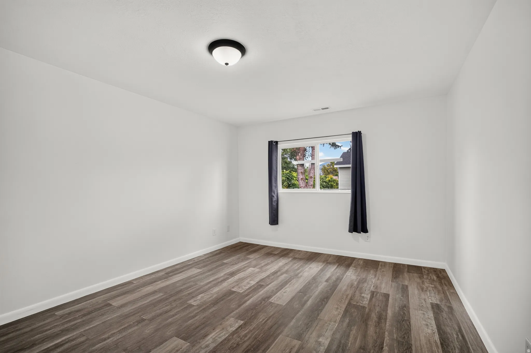 Laminate wood-finish flooring, white walls, and a single window with natural light