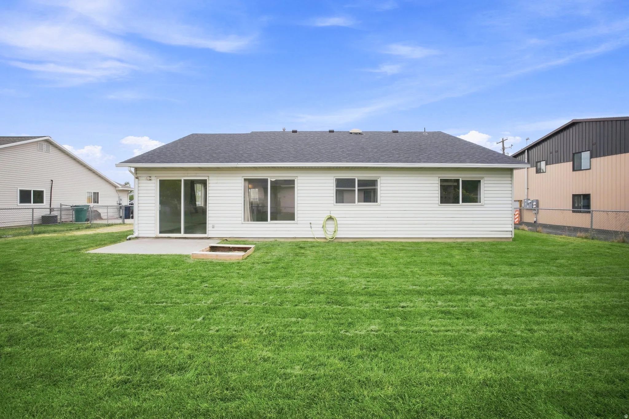Expansive backyard featuring a manicured lawn, concrete patio, and built-in planter