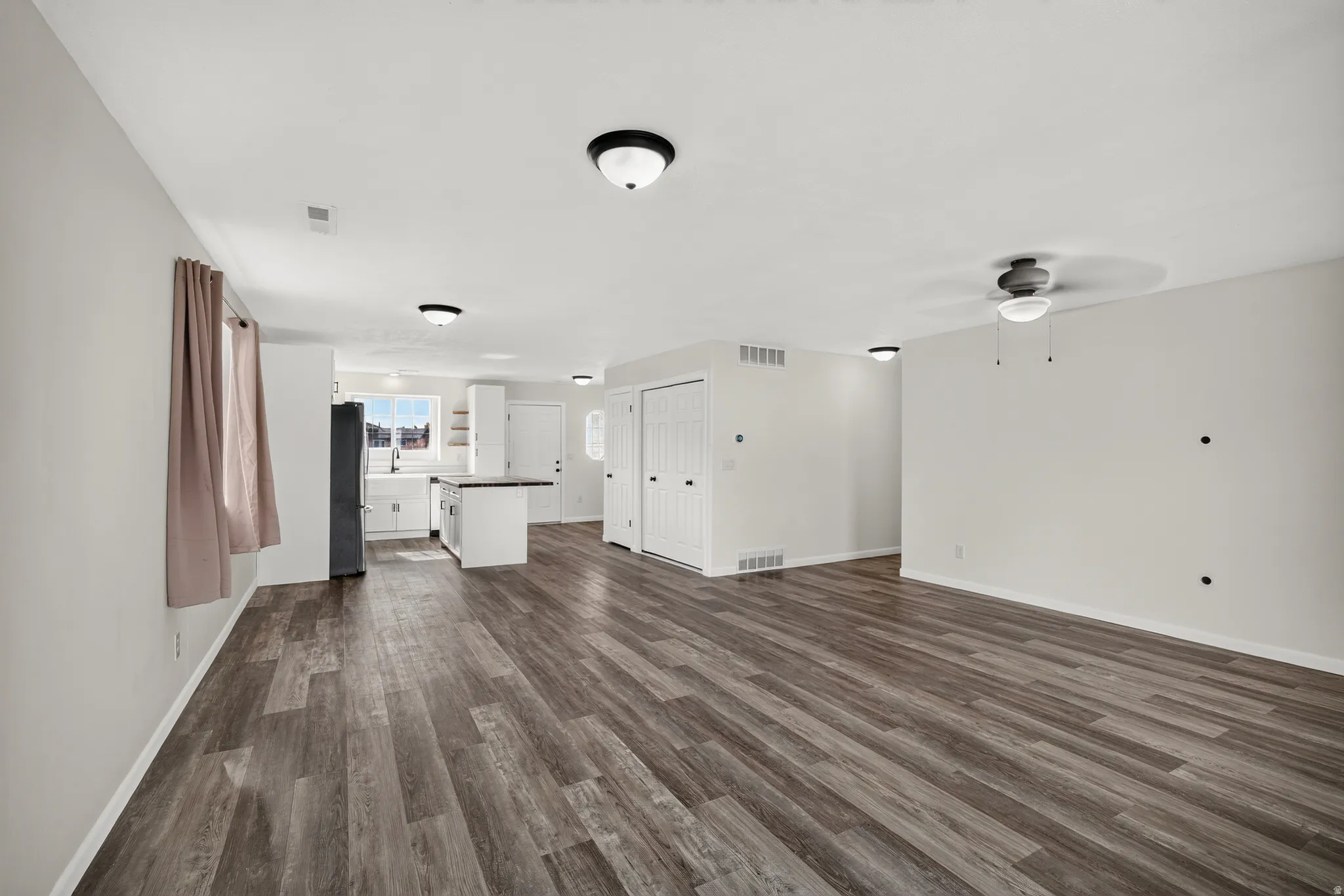 Wood-finish flooring throughout, bright white walls, recessed lighting, ceiling fan, and built-in closet storage
