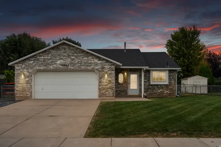 Brick exterior with an attached two-car garage, concrete driveway, and a manicured lawn