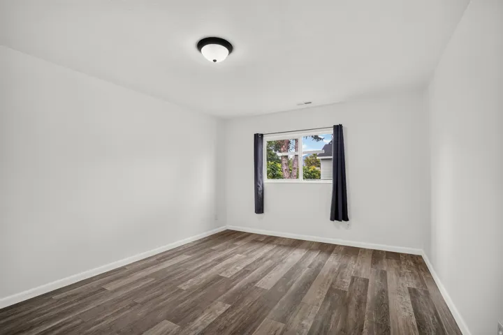 Laminate wood-finish flooring, white walls, and a single window with natural light