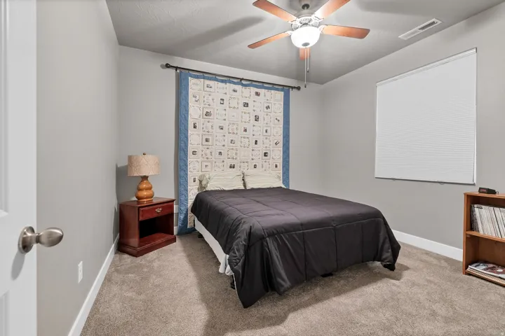Carpeted room featuring a ceiling fan with light fixture and a window with blinds