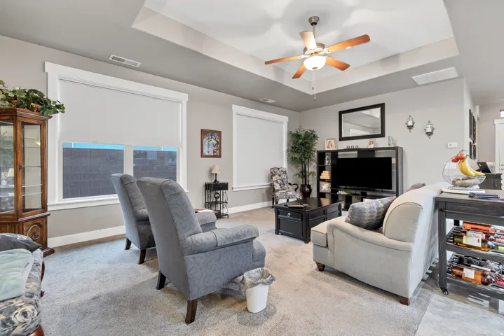 Tray ceiling with a ceiling fan light fixture, recessed lighting, and wall-mounted sconces