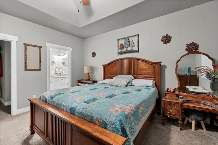 Tray ceiling, neutral wall color, carpeted flooring, and a ceiling fan