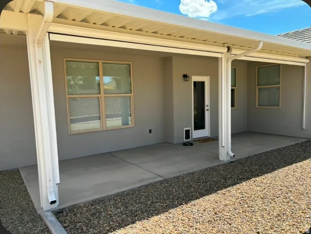Covered patio with a concrete surface, exterior lighting fixture, and gravel landscaping