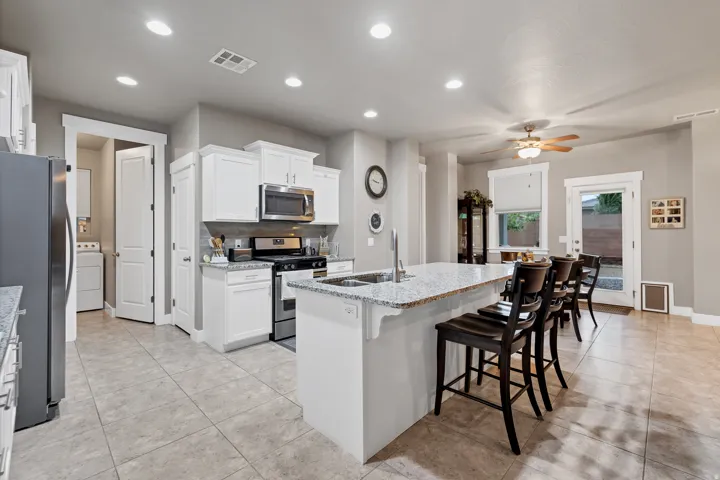 Kitchen featuring recessed lighting, white cabinetry, stainless steel appliances, a center island with sink, and tile flooring