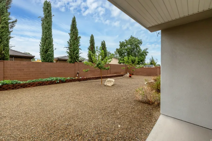 Expansive rear yard featuring gravel landscaping, a perimeter block wall, and mature trees