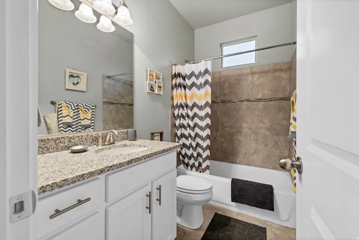 Bathroom featuring a single vanity with a granite countertop, undermount sink, and brushed nickel hardware