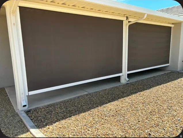 Patio with two roll-down shades, white support columns, and a rain gutter system