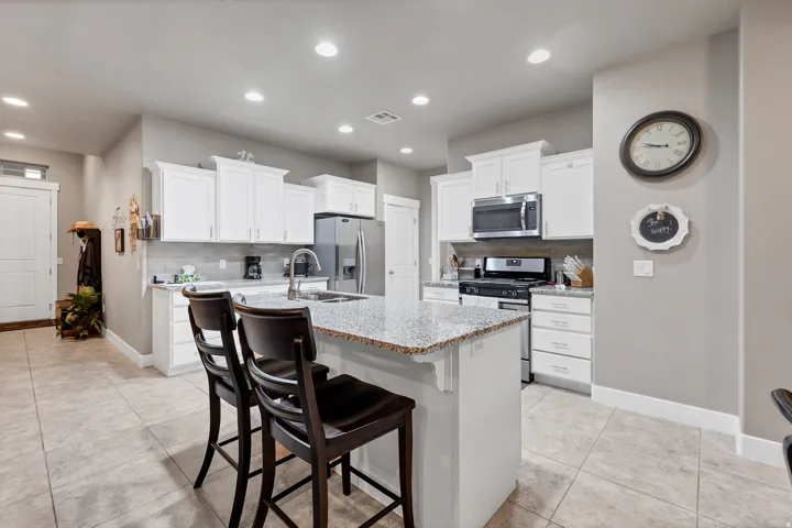 Kitchen featuring a central island with countertop seating, white cabinetry, stainless steel appliances, and tile flooring