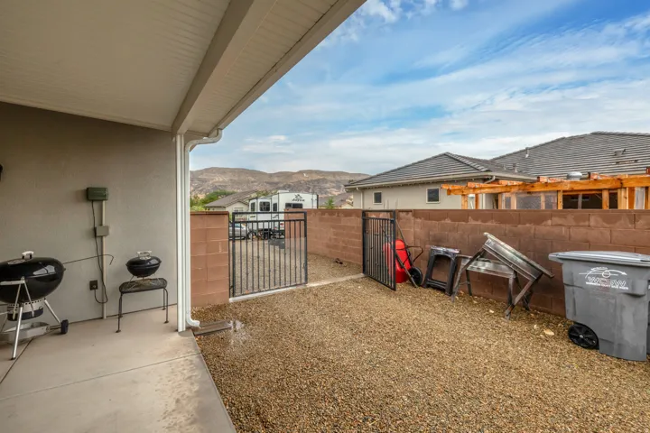 Covered patio with concrete flooring, gravel landscaping, and block wall fencing