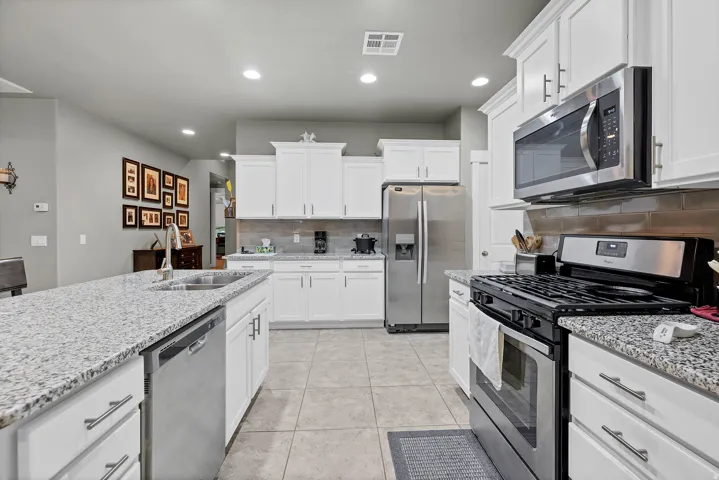 Kitchen featuring white cabinetry, light-toned countertops, stainless steel appliances, and tile flooring
