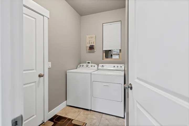 Laundry area with tile flooring, neutral wall tones, and natural light from a window with blinds