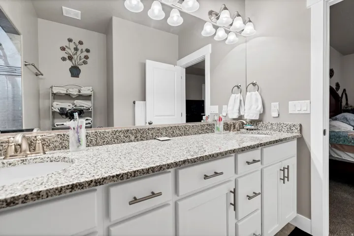 Double vanity with white cabinetry, granite-look countertops, and brushed nickel hardware