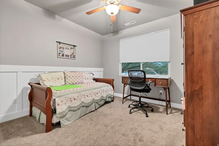 Carpeted room with a ceiling fan, a window, and wainscoting
