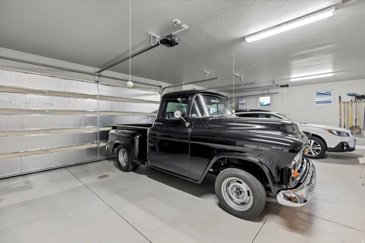 Spacious garage featuring a concrete floor, insulated garage door, built-in shelving, and overhead lighting