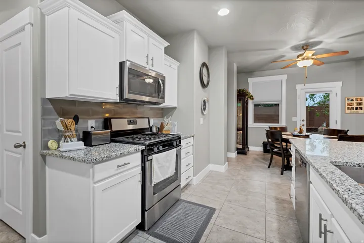 White shaker cabinetry with granite countertops, stainless steel appliances, and a tile backsplash