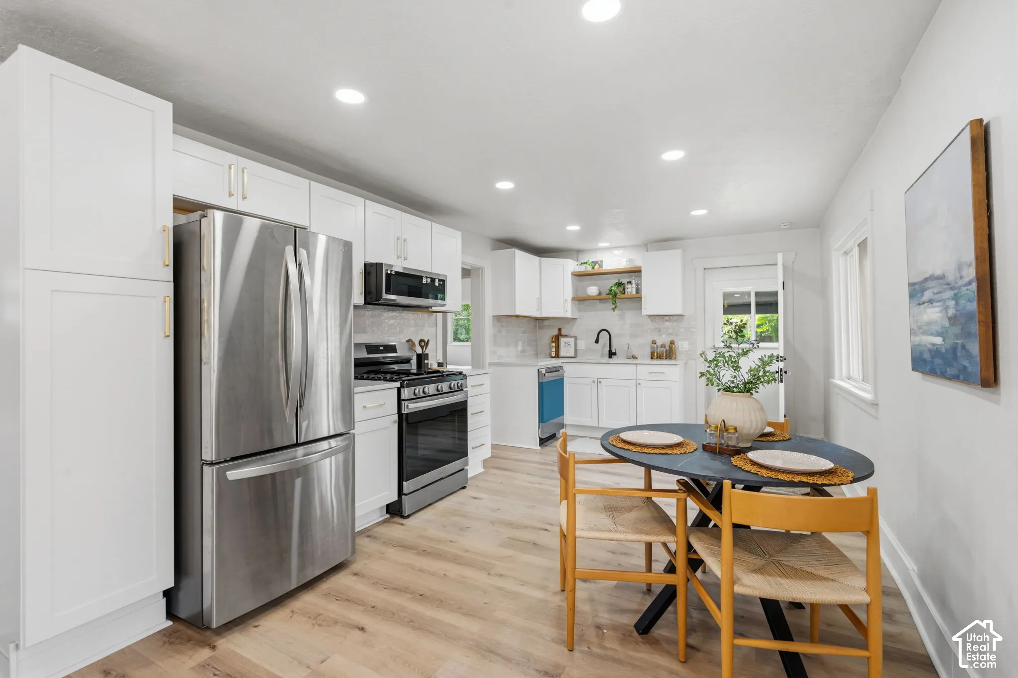 Kitchen featuring wood-finish flooring, white cabinetry, stainless steel appliances, and recessed lighting
