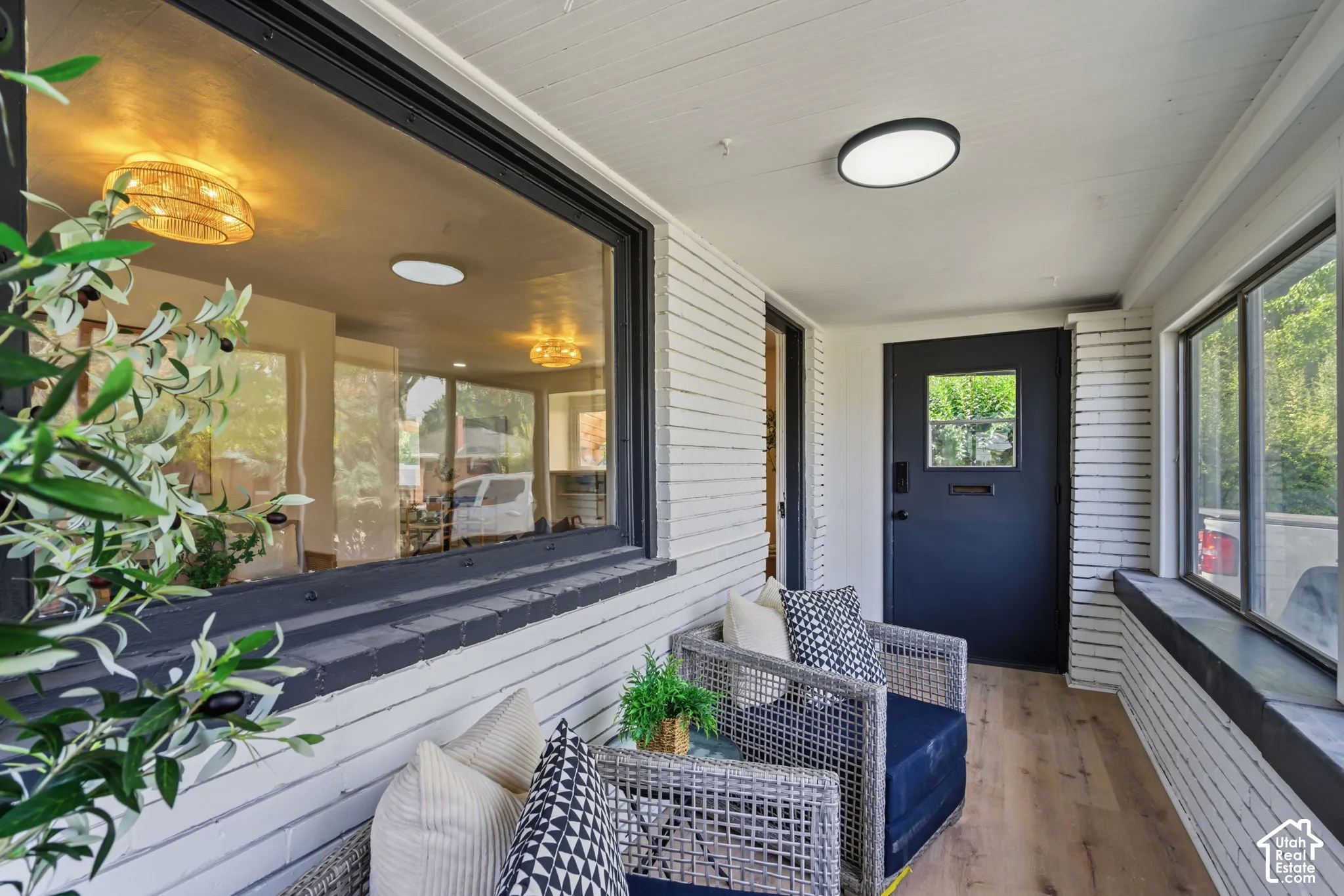 Welcoming front entry showcasing white horizontal siding, a navy blue entry door with sidelights, and expansive windows flooding the space with natural light