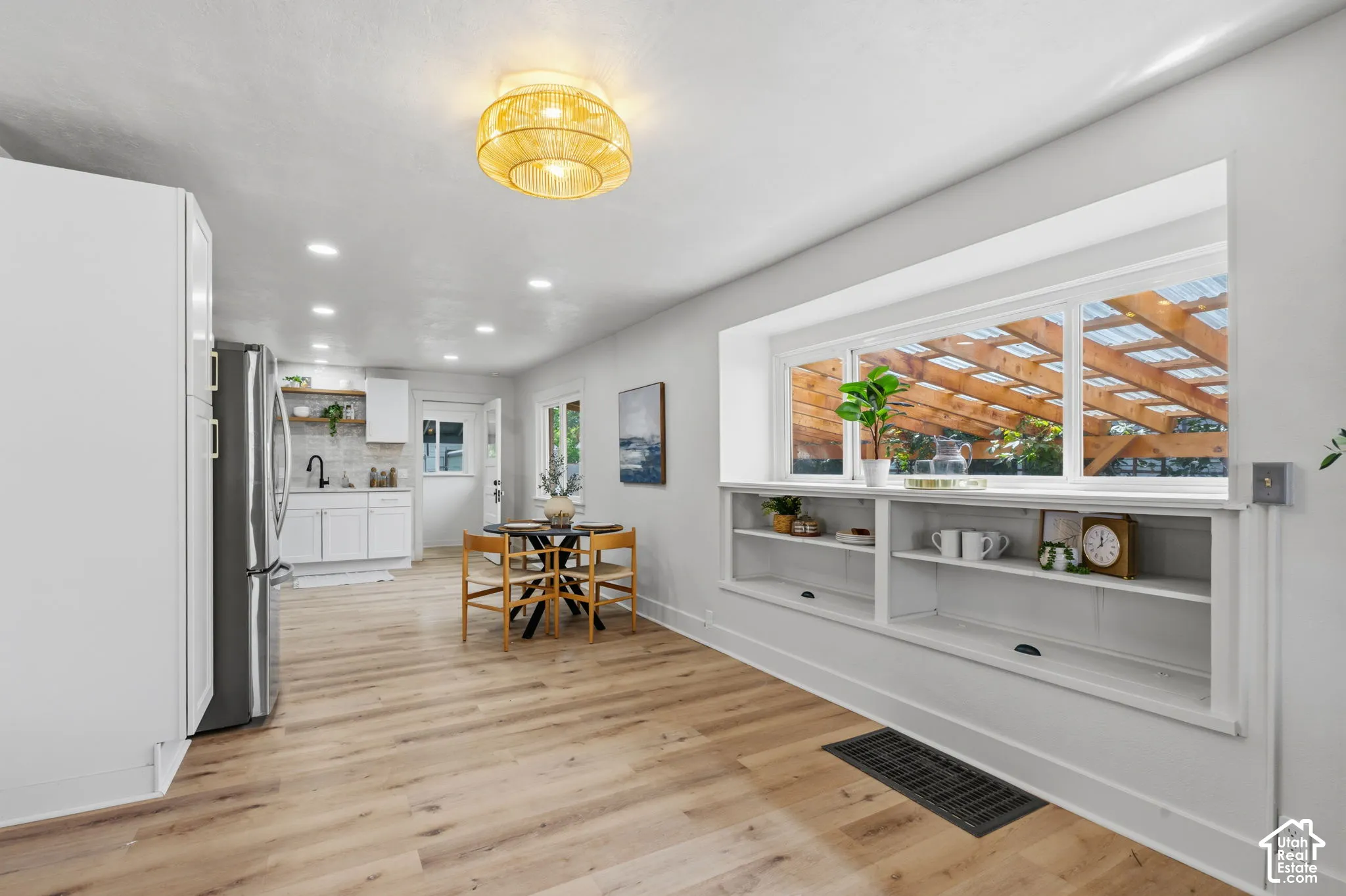 Light wood-finish flooring complements white walls, recessed lighting, and a window with integrated shelving