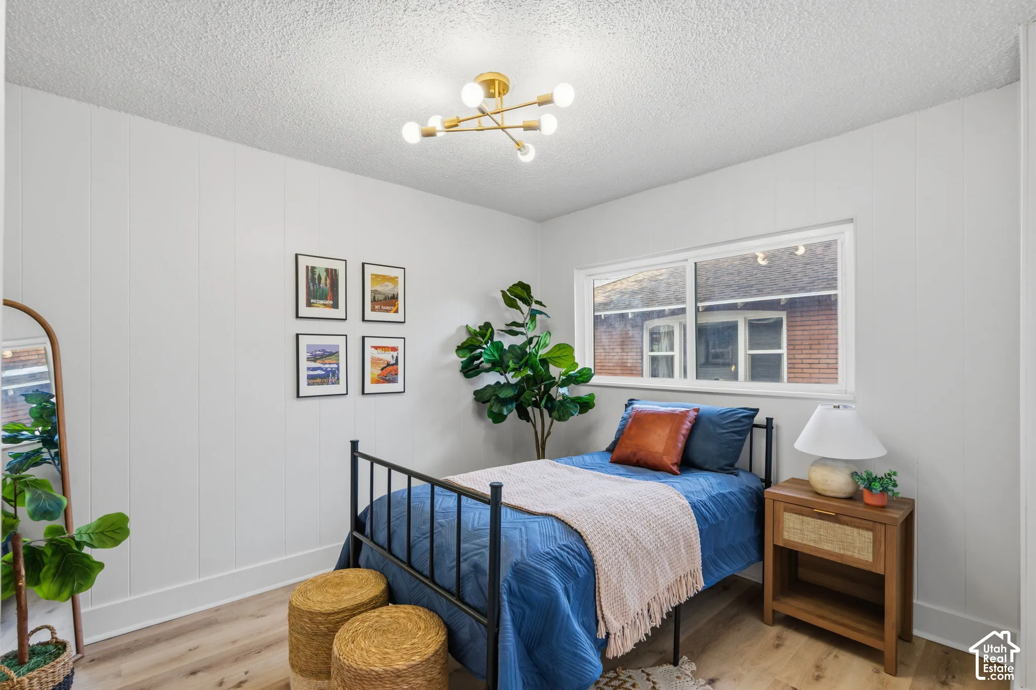 Wood-finish flooring, white paneled wall treatment, modern ceiling light fixture, and a window providing natural light