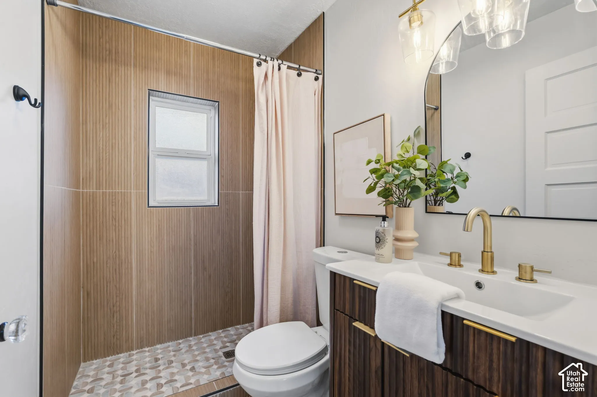 Modern bathroom featuring a wood-finish vanity with gold-tone hardware, a white rectangular sink, and a gold-tone faucet