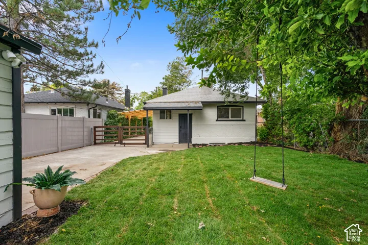 Expansive lawn area with mature trees, a paved driveway, and a privacy fence
