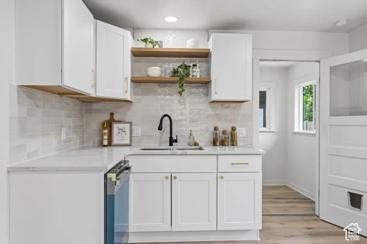 White shaker cabinetry, quartz countertops, subway tile backsplash, matte black faucet, and wood-finish flooring