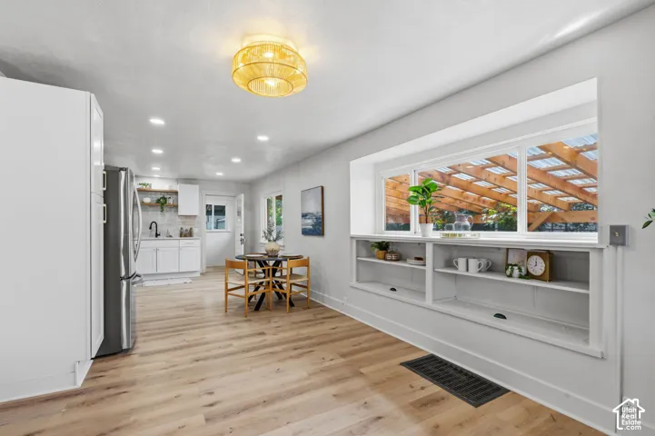 Light wood-finish flooring complements white walls, recessed lighting, and a window with integrated shelving