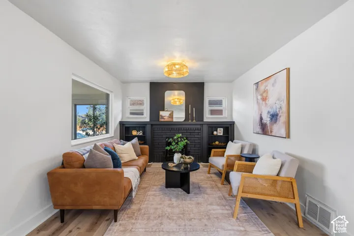 Wood-finish flooring, recessed lighting, and a prominent black brick fireplace with built-in shelving
