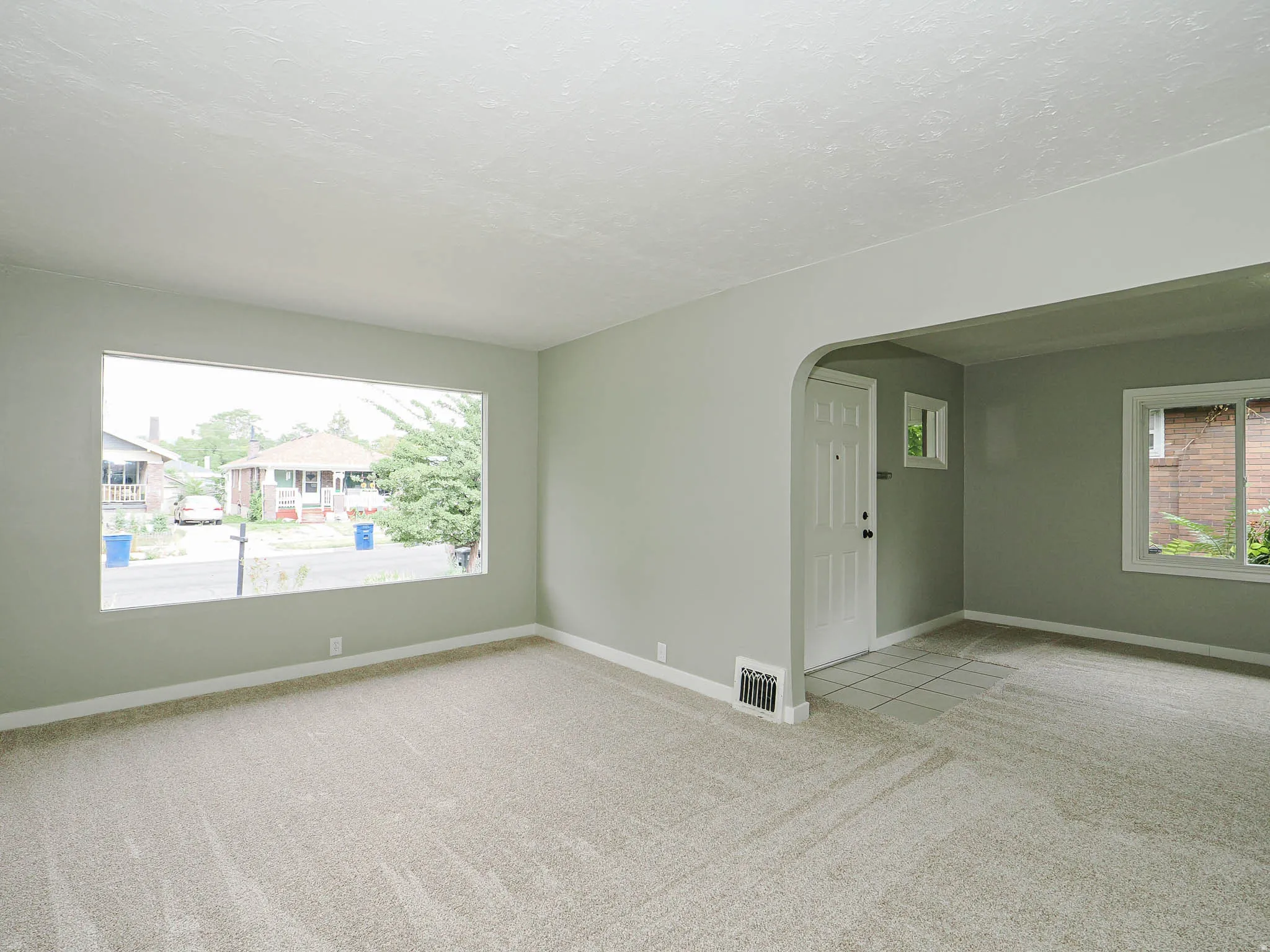 Bright living space with large street- facing window flooding the room with natural light