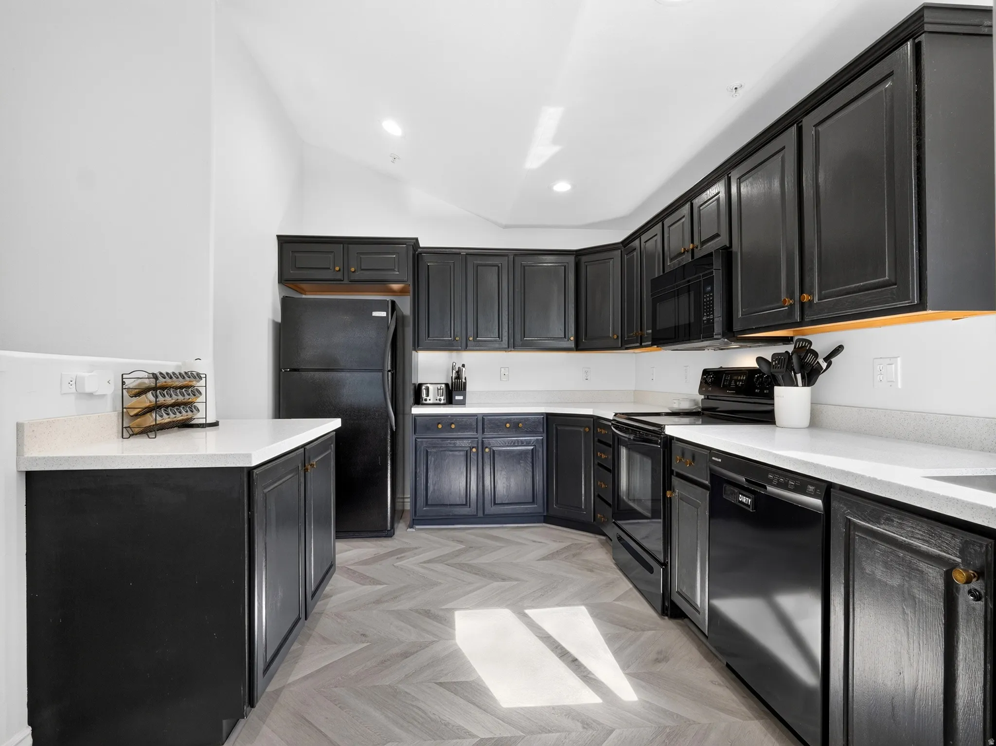 Modern kitchen featuring sleek black cabinetry with brass hardware accents, white subway tile backsplash, and white quartz countertops