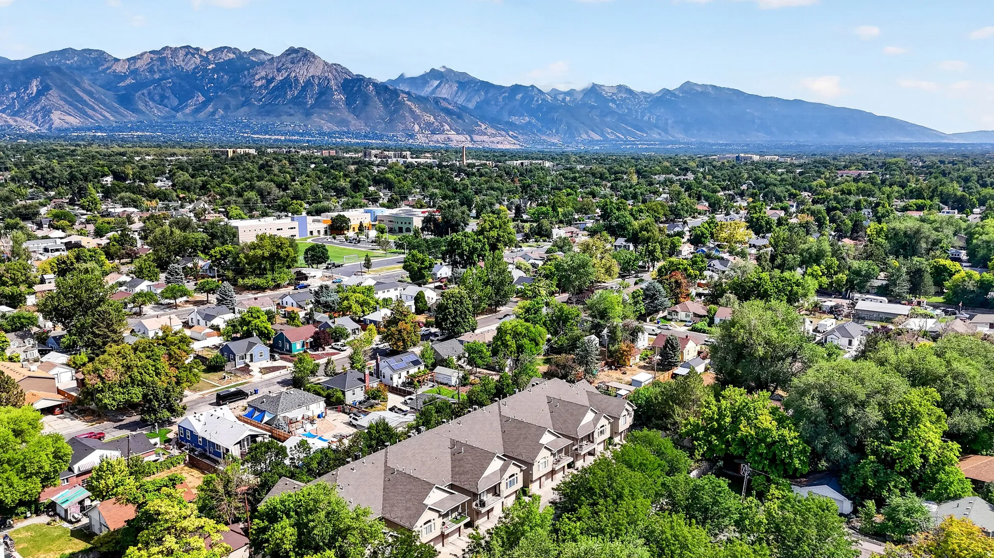 Aerial perspective showcasing a substantial residential estate set within a mature tree-lined neighborhood, with manicured landscaping and established vegetation throughout the property