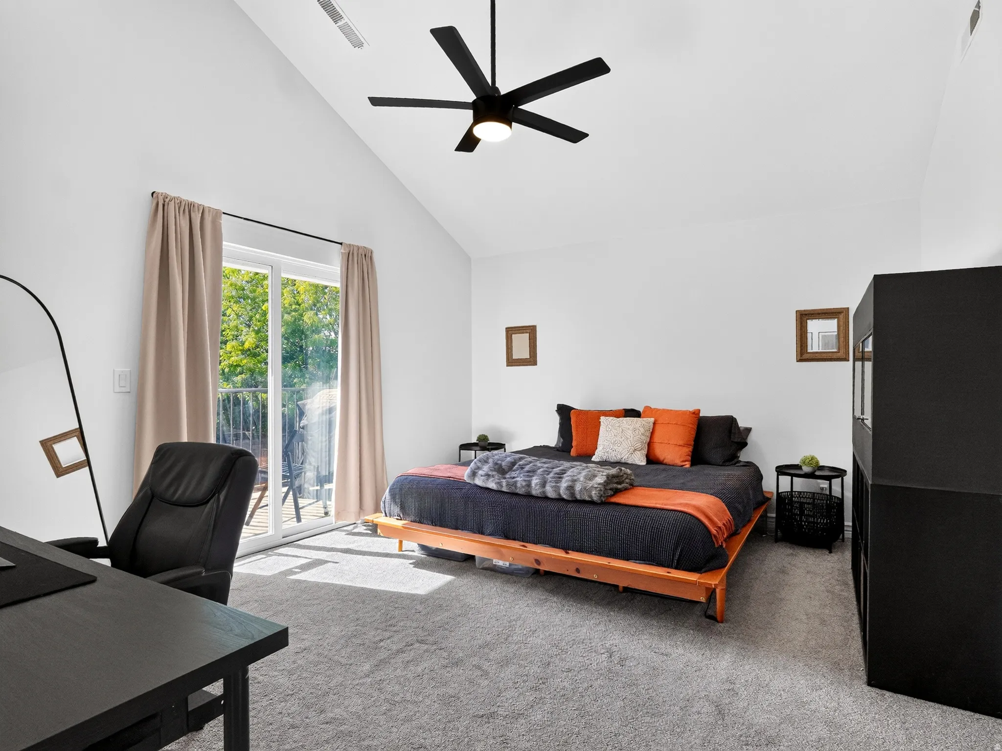 Bright bedroom suite featuring vaulted ceilings, a ceiling fan with dark finish, and expansive glass doors opening to outdoor space