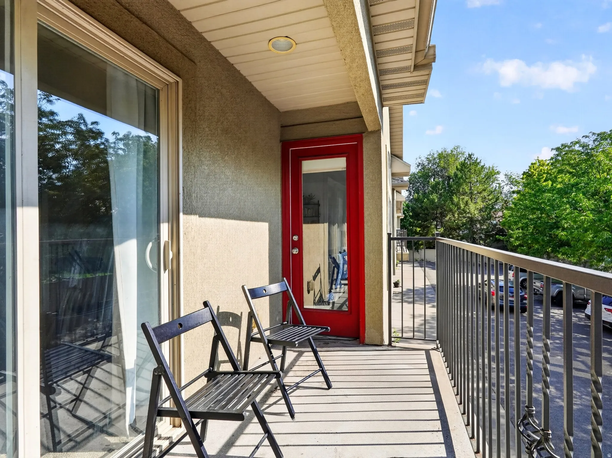 Balcony with a sliding glass door, recessed lighting, red exterior door, and metal railing